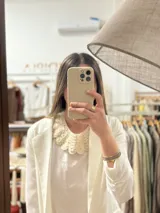 Cuello desmontable tejido a mano en lana merino color crudo, con diseño calado y borde festoneado.