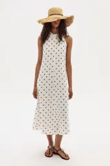 Vestido midi blanco con lunares marrones, escote halter y corte en línea A. Confeccionado en lino 100% natural con terminación metalizada.