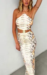 Vestido midi con estampado de cebra, corte ajustado y escote halter. Incluye cinturón dorado.