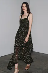Vestido negro con estampado floral, escote recto y tirantes finos. Detalle de aplicación de hilo metalizado, lentejuelas y puntilla combinadas a tono. Bajo asimétrico.
