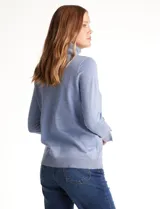 Polera tejida en hilado fino color verde oscuro, de manga larga con tajo en el puño y cuello alto.