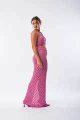Conjunto tejido de color fucsia brillante, compuesto por un top corto con tirantes finos y una falda larga con abertura lateral.