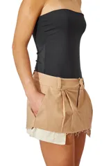 Mini falda color beige de gabardina elastizada con bolsillos laterales y ruedo desflecado.