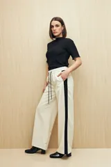 Pantalón de jogging color crema con cintura elástica, cordón ajustable y franja lateral negra.