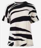 Blusa de viscosa color crudo con estampado abstracto en negro. Tiene cuello redondo y mangas cortas con recorte.