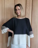 Buzo de punto con mangas 3/4, corte amplio y diseño a bloques de color negro, gris y blanco.