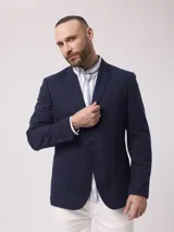 Saco azul marino de piqué con cuello con solapas y bolsillos de plastrón. Mangas con coderas y bajo con abertura en espalda.