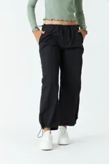 Pantalón negro de tiro medio, corte recto cropped y bolsillos laterales.