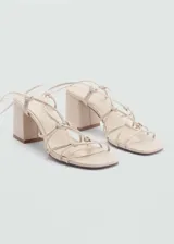 Sandalias color beige con tacón bloque y tiras finas que se atan alrededor del tobillo.