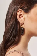 Aros colgantes dorados con forma de argolla pequeña y dije en forma de cuerno de resina con incrustaciones de strass.