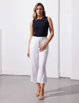 Pantalón capri de lino color blanco con rayas verticales celestes y amarillas, pretina elastizada, bolsillos delanteros y botones decorativos.