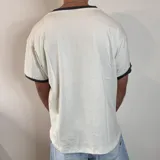 Remera negra de corte regular con cuello redondo y ribetes en contraste color blanco en el cuello y los puños. Presenta un pequeño logo bordado en el pecho.