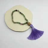 Handmala de fluorita con 27 cuentas de 8 mm de diámetro, separadores de hilo violeta, cuenta guru de madera y borla de hilo de seda lila.