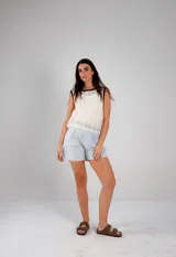 Blusa blanca de tejido calado, sin mangas y con cuello redondo ribeteado en negro.