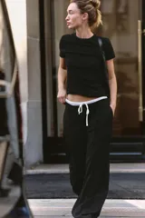 Pantalón gris con estampado de espiga, de tiro alto con doble cintura elástica ajustable con cordón. Presenta pinzas frontales, bolsillos delanteros y falso bolsillo de vivo en espalda. Pernera ancha.