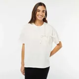 Camiseta blanca de algodón con cuello redondo y mangas cortas. Presenta un bolsillo en el pecho con dos lazos decorativos.