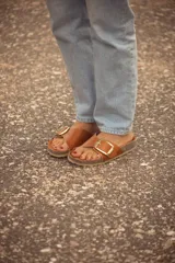 Sandalias de cuero color marrón con hebilla metálica plateada.