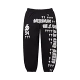 Pantalón de jogging negro con cintura elástica y cordón ajustable. Estampado con el logo de Supreme y otros diseños gráficos en color blanco.