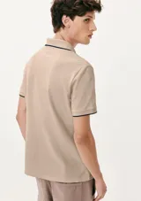 Camisa polo color rosa claro con cuello clásico, tapeta de dos botones y bordado de logo en el pecho. Presenta ribete azul marino en cuello y mangas. Corte clásico.