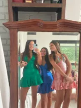 Vestido corto de lentejuelas color verde oliva, con escote en V, breteles finos cruzados en la espalda, cut-outs laterales y volado en el ruedo.