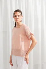 Blusa de lino color rosado, de corte holgado, con cuello redondo y detalle de encaje en ruedo y mangas.
