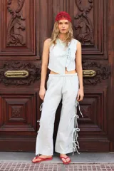 Pantalón largo color celeste con finas rayas verticales blancas, de corte suelto y cintura elástica. Presenta aberturas laterales con lazos.