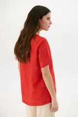 Blusa manga corta color rojo con cortes laterales y abertura abotonada en la espalda. Los pespuntes a contratono resaltan el escote y los cortes.