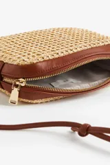 Cartera bandolera rectangular de paja color beige, con detalles y correa fina ajustable de cuero marrón.