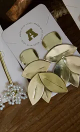 Caravanas doradas de bronce con diseño de hojas, ideales para complementar cualquier outfit.