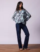 Camisa de gasa estampada a rayas verticales de color celeste, blanco, naranja y marrón. Tiene cuello con solapa, escote en V, abertura central con botones, bolsillo aplicado en el pecho y terminación anudada en la parte delantera.