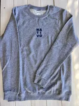 Buzo gris melange de corte clásico con cuello redondo, puños y cintura acanalados. Estampado frontal con el logo de la marca "Nativo" en azul marino.