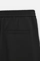 Pantalón negro de corte regular, confeccionado en tejido con viscosa, con cintura elástica, bolsillos frontales y trasero de vivo.