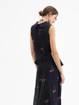 Top sin mangas color azul marino con cuello camisero y peplum en la cintura. Presenta un estampado de cerezas.