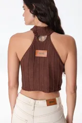 Top halter marrón oscuro, estilo chaleco, confeccionado con parches de cuero cosidos en patrón de rombos con costura de ganchillo visible. El cuello es de punto trenzado.