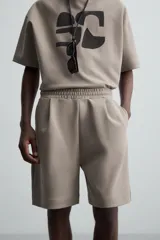 Bermuda color arena de tejido interlock de algodón con elasticidad, corte relaxed fit, cintura elástica ajustable con cordón interior, bolsillos laterales y bolsillo trasero de plastrón.