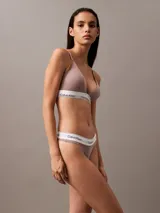 Conjunto de ropa interior Calvin Klein color topo, compuesto por un corpiño triangular con breteles finos y una colaless, ambos con banda elástica blanca con el logo de la marca.