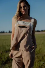 Conjunto de top y pantalón color beige. El top es de breteles anchos, con escote cuadrado y detalle de bordado en el frente. El pantalón es de corte recto y ancho, con bolsillos laterales y cintura con elástico y botones.