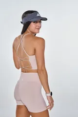 Conjunto deportivo color beige, compuesto por un top con tiras cruzadas en la espalda y un short de calce ajustado.