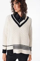 Sweater de estilo clásico color crudo, con cuello en V y diseño de puntos texturizados en el cuerpo y las mangas.