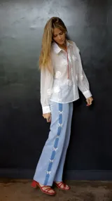 Pantalón de jean celeste con spandex y detalle de apliques de mariposas plateadas en los laterales. Corte recto y tiro medio.