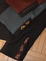 Chaqueta corta de terciopelo azul marino con cuello mao, mangas abullonadas, cierre frontal con botones dorados y bordados florales con cuentas azules.