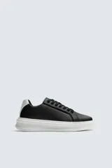 Zapatillas deportivas negras con detalle en blanco en el talón y suela blanca con volumen.