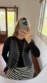 Chaleco negro de ecocuero con tachas doradas.