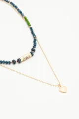 Collar doble con una cadena de piedras facetadas azules y verdes, y una cadena dorada de bolitas con un dije de corazón dorado.