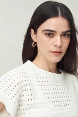 Chaleco tejido color crudo con diseño calado, cuello redondo y mangas cortas. Corte holgado.
