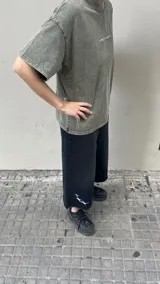 Bermuda de jean negra de corte ancho (baggy) y largo 3/4, con bordados de estrellas blancas en la parte inferior de la pierna izquierda.