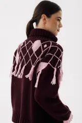 Sweater tejido de punto color crudo con cuello alto y diseño de rombos marrones con flecos.