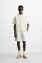 Bermuda relaxed fit color blanco confeccionada en tejido interlock de algodón con elasticidad. Cintura elástica ajustable con cordón interior. Bolsillos laterales y detalle de bolsillo trasero de plastrón.