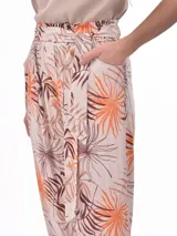 Pantalón babucha de tela estampada con hojas en tonos rosa, naranja y azul, con cintura elastizada y lazo para ajustar.
