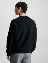 Buzo negro de algodón modal suave con cuello redondo, puños y bajo de canalé. Presenta un logo de Calvin Klein en la misma gama de tonos en el pecho.